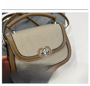 Close-up of woven fabric texture and metal twist lock on the brown saddle bag