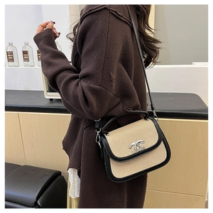 Détail du sac selle en paille et cuir noir avec fermoir en métal argenté sur un modèle