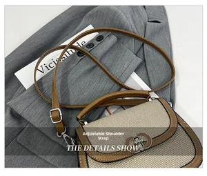 Detail showing adjustable leather shoulder strap with silver buckle on a bicolor saddle bag
