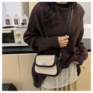 Détail d'un sac selle vintage avec texture tissée, finitions cuir et boucle argentée