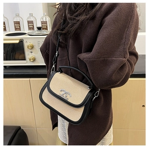 Détail du sac selle tissé beige avec garniture en cuir noir et boucle en métal argenté