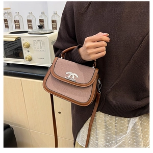 Détail du sac selle en tissu rose et cuir marron avec fermoir à nœud métallique