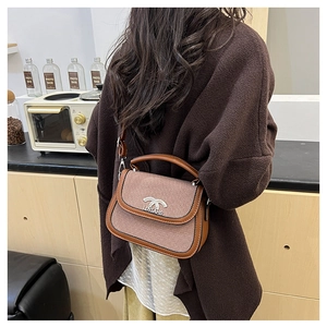 Détail du sac selle vintage avec texture tweed et garniture en cuir marron sur modèle