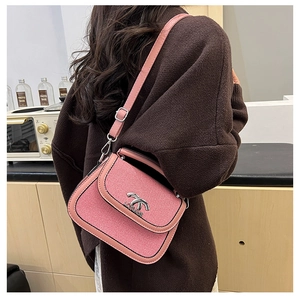 Détail du sac besace rose avec fermoir rotatif argenté et bordures en cuir lisse