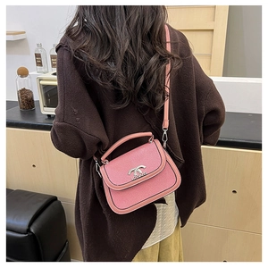 Détail du sac selle rose avec fermoir argenté sur un mannequin en manteau marron