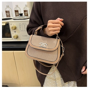 Détail du sac selle tissé avec bordure en cuir et logo argenté dans un cadre lifestyle