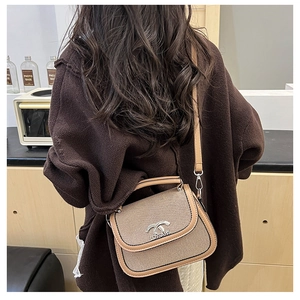 Détail du sac selle bicolore avec boucle en métal et bandoulière porté par un mannequin