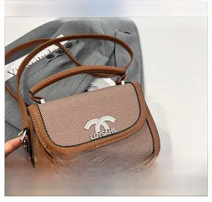 Vue détaillée du sac besace en cuir marron avec empiècement tissé et logo métallique