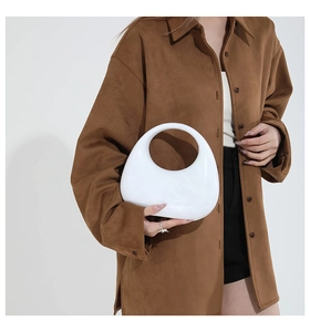 Detailed close-up of a white acrylic half-moon handbag with a circular cutout handle