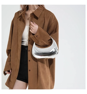 Chic silver mirror crescent bag paired with a brown suede shirt for a modern minimalist look