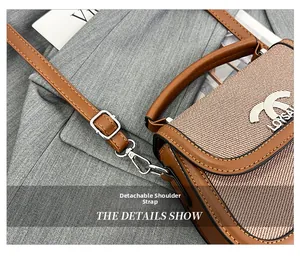 Détail de la bandoulière amovible avec ferrures dorées sur un sac de selle marron