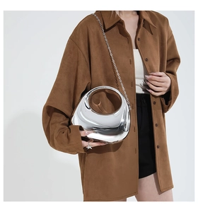Detail of futuristic mirrored silver moon bag with unique cutout handle and thin chain strap
