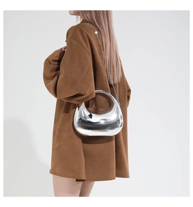 Detail of silver mirror finish crescent bag with integrated handle and chain strap