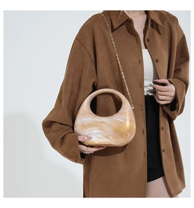 Close-up of yellow marble pattern acrylic handbag with gold chain on model
