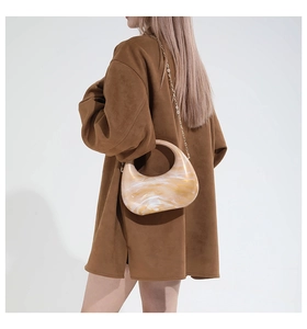 Detail view of acrylic half-moon bag with golden marble texture and elegant metal chain