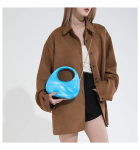 Detail of blue marble acrylic crescent bag with golden chain on brown shirt
