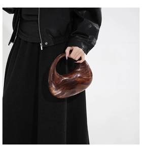 Close-up of stylish amber marble acrylic handbag featuring a unique curved hollow design