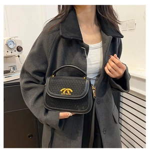 Detail of a black textured crossbody bag featuring gold metal logo and leather trim