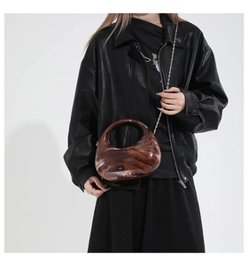 Detail of amber marble texture crescent bag styled with a black leather jacket