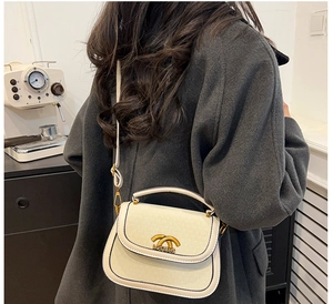 Detail of off-white crossbody saddle bag with gold hardware and adjustable strap