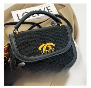 Close-up of black woven texture with golden metal curved logo on fashionable saddle bag
