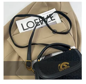 Close-up of black woven texture handbag featuring gold hardware and adjustable strap