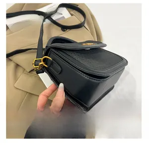 Detail shot of black saddle bag with woven texture lid and elegant gold hardware