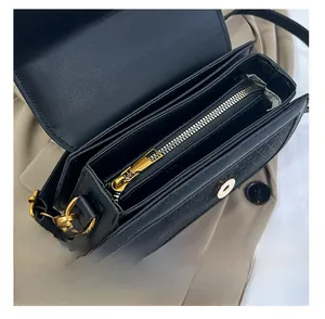 Detailed interior of black leather handbag featuring three compartments and gold hardware