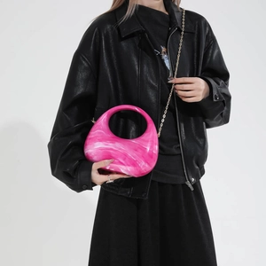 Pink marble acrylic crescent bag with round handle and gold chain strap on black leather jacket