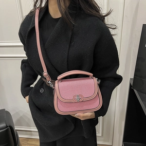 Pink striped saddle bag with metal buckle shown on a model wearing a black coat