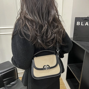 Fashionable beige woven saddle bag with black leather trim and silver metal interlocking clasp