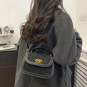 Retro black leather and tweed saddle bag with gold logo shown on female model back