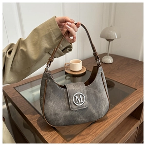 Detail of gray crescent bag with brown leather trim and silver metal M logo clasp