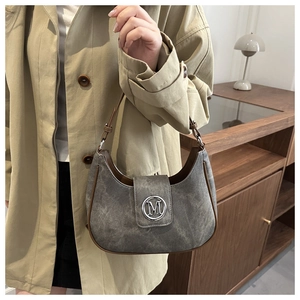 Detail of grey suede crescent bag with brown leather trim and silver metal M logo