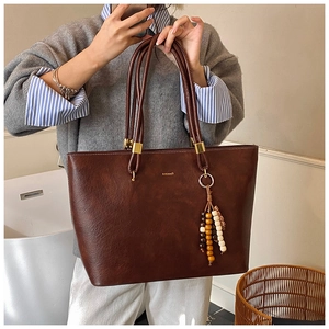 Détail d'un cabas rétro en cuir marron foncé avec perles colorées et logo doré