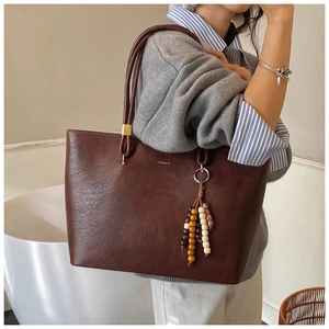 Détail du grand sac cabas en cuir marron vintage avec pendentif en perles et bois