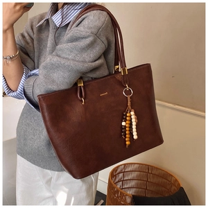 Détail d'un sac cabas marron foncé en similicuir avec gland perlé et garnitures dorées