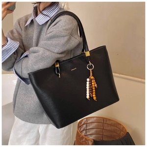 Détail du sac cabas en cuir grainé noir avec logo BAIMIAO doré et charme perlé