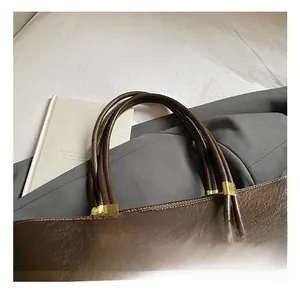 Détail du sac fourre-tout en cuir huilé marron avec ferrures dorées et perles en bois