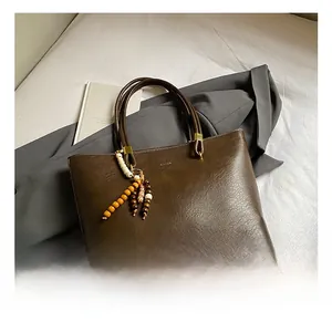 Gros plan d'un grand sac cabas vintage marron avec texture cuir et accessoire de perles