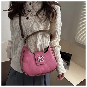 Detail of pink suede saddle bag with brown leather trim and silver M logo buckle