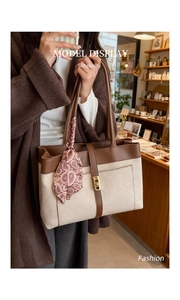 Detail of canvas tote bag featuring brown leather trim and elegant silk scarf accessory