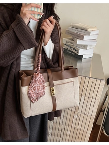 Detail of canvas tote bag with brown leather trim, metal clasp and paisley scarf accent
