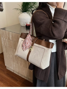 Detail of canvas tote bag with brown leather trim and stylish paisley silk scarf on handle