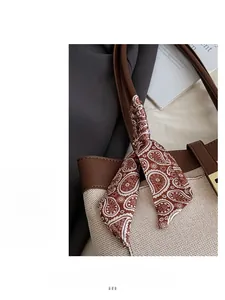 Detail of canvas tote bag with brown leather handles and decorative paisley print silk scarf