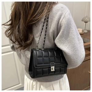 Detail of black quilted leather shoulder bag with silver chain strap and metal lock