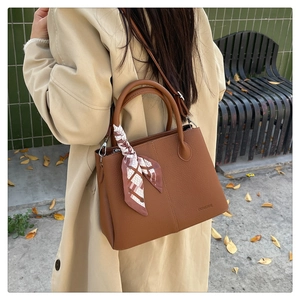 Brown lychee leather tote bag with silk scarf detail shown in autumn outdoor scene