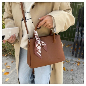 Close-up of brown lychee grain leather tote bag with silk scarf and adjustable strap