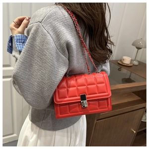 Detail of red quilted leather crossbody bag with silver chain strap and square metal lock