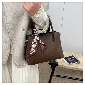 Detail of dark brown litchi grain leather tote bag featuring a decorative printed silk scarf
